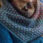 Knit cowl in bubble stitch with a gradient running from teal through coral to rust
