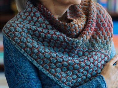 Knit cowl in bubble stitch with a gradient running from teal through coral to rust