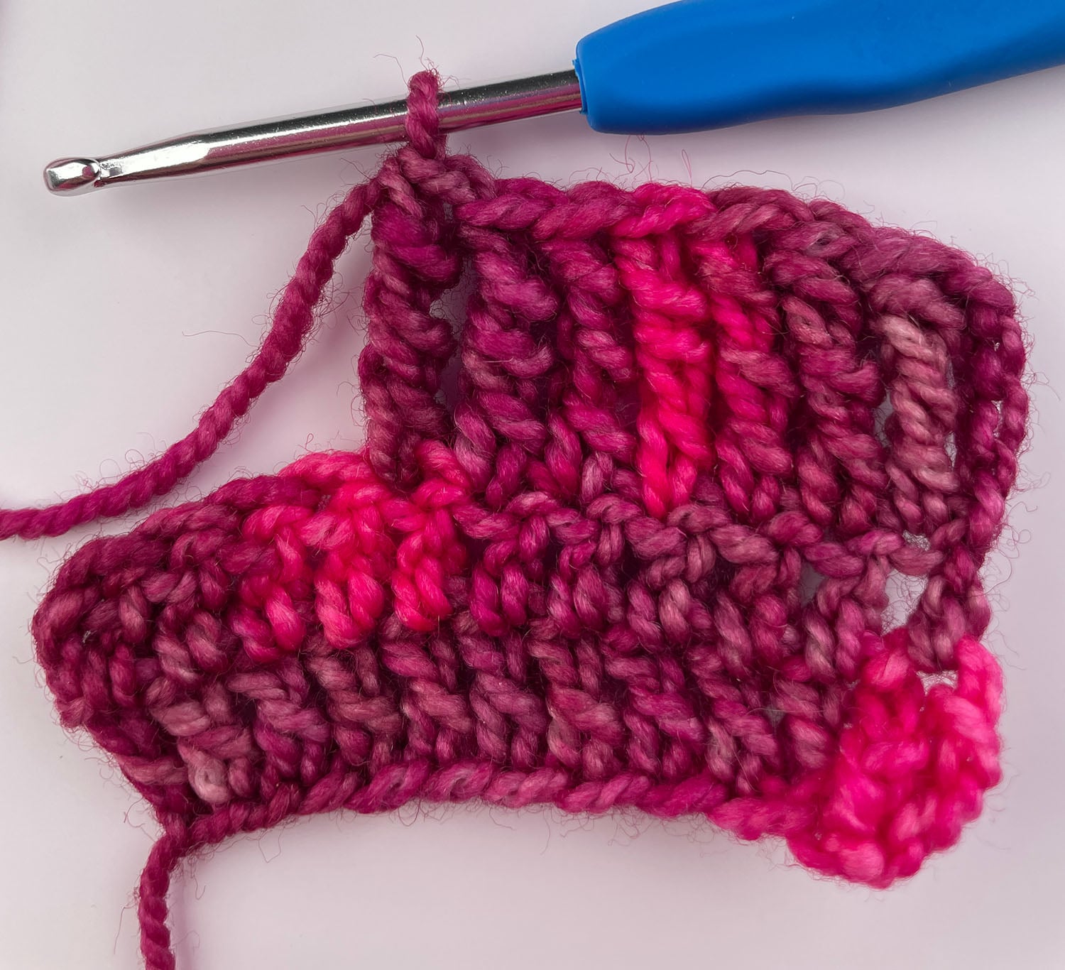 A finished double treble crochet stitch standing tall beside the row.